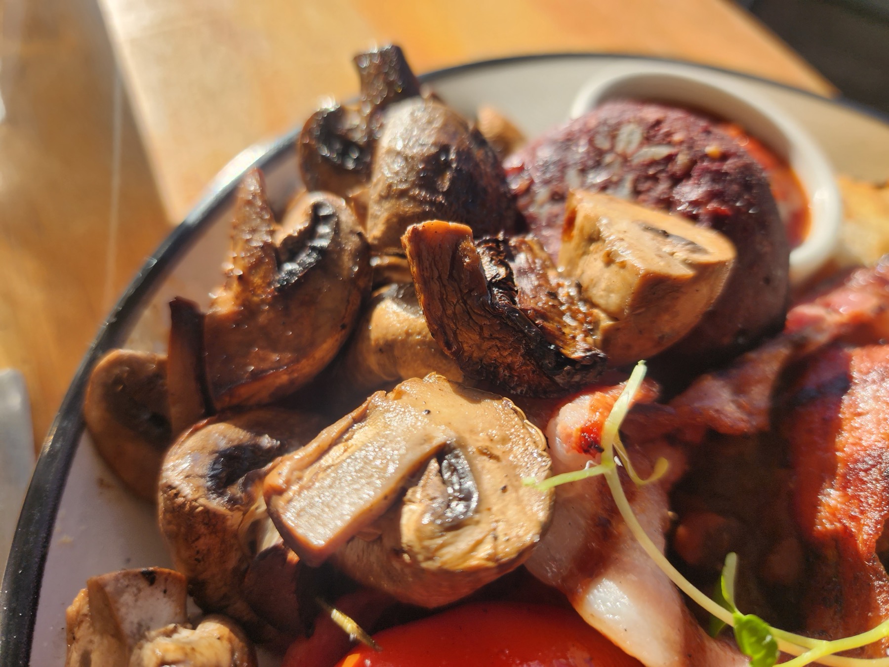 Close-up of grilled mushrooms, black pudding and bacon on the plate